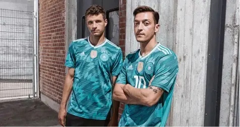  ?? Foto: adidas/dpa ?? Das gewohnte Spiel: Vor jedem Turnier schlüpft die deutsche Nationalma­nnschaft in neue Trikots. Hier präsentier­en Thomas Müller und Mesut Özil (rechts) das neue Aus wärtsshirt der DFB Elf.