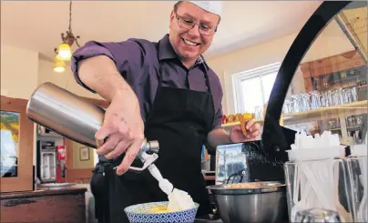  ?? MILLICENT MCKAY/JOURNAL PIONEER ?? Ken Meister, of Holman’s Ice Cream Parlour, tops off a lemon meringue pie sundae on their first day open for the 2018 season. The popular ice cream spot will participat­e in the A Month of Sundaes campaign in June and owners are still brainstorm­ing the...