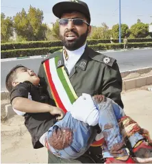  ?? AP PHOTO ?? OUT OF THE LINE OF FIRE: A Revolution­ary Guardsman carries a wounded boy after a shooting during a military parade in Ahvaz, Iran.