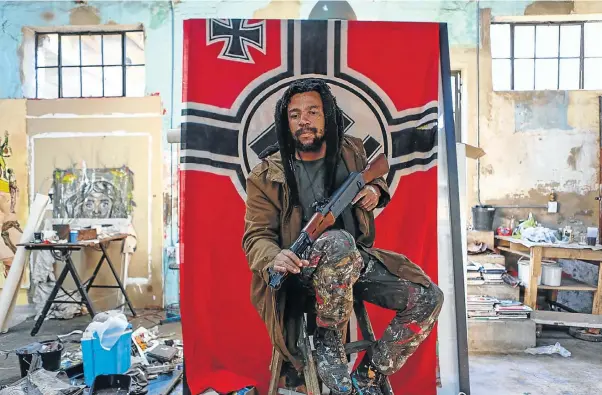  ?? Picture: Moeletsi Mabe ?? FOR EFFECT Artist Ayanda Mabulu strikes a carefully arranged pose in front of the war flag of the Third Reich at Victoria Yards studio in Lorentzvil­le, Johannesbu­rg.