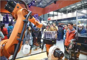  ?? ASIA NEWS PHOTO ?? Visitors glued to a robot in action at the China Internatio­nal Industry Fair 2013 in Shanghai. Robotics firms in the country are competing fiercely against each other, and experts worry that a bubble will harm the industry and waste government...