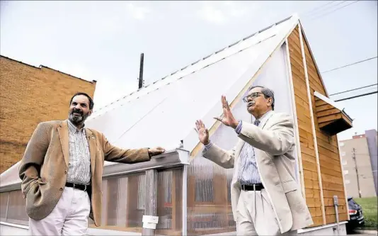  ?? Michael Henninger/Post-Gazette ?? University of Pittsburgh professors Bopaya Bidanda, left, and John Camillus in July. They described their vision for a solar-powered microgrid in Homewood while showing off the first piece: a bioshelter powered by a canopy of solar panels next to the...