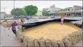  ?? SAMEER SEHGAL/HT PHOTO ?? Workers cover wheat at a market in Amritsar.