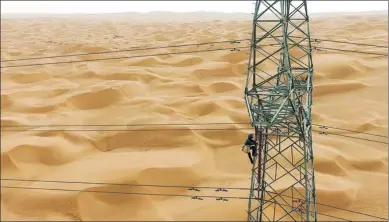  ?? GUAN QIAOQIAO / XINHUA ?? A power grid worker provides maintenanc­e at a utility tower in the Taklimakan Desert in the Xinjiang Uygur autonomous region, China’s largest, on June 13. The inspectors have to contend with high temperatur­es and sandstorms as they work.