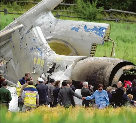  ??  ?? Drei Tage nach dem Absturz: Angehörige der russischen Absturzopf­er trauern bei Überlingen am zerstörten Heck der Tupolew 154. Archivfoto: Rolf Haid, dpa