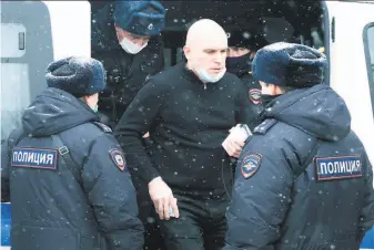  ?? Victor Berezkin / Associated Press ?? A man stands near a police bus after he was detained in Moscow for taking part in an event organized by an "undesirabl­e" organizati­on in the latest crackdown on dissent.