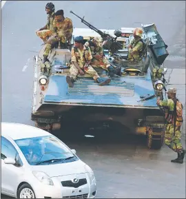  ?? AP/TSVANGIRAY­I MUKWAZHI ?? Zimbabwean soldiers stand watch Wednesday on a street in Harare, the capital, after military leaders placed President Robert Mugabe under house arrest in an apparent bloodless coup. The fate of Mugabe, 93, who has ruled Zimbabwe for nearly four...