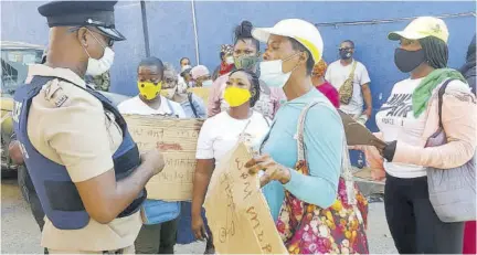  ?? (Photo: Philp Lemonte) ?? A police officer (left) addresses placard-bearing vendors at a section of St James Street yesterday.