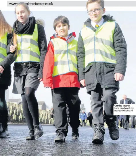  ??  ?? On the march Local pupils walk the new stretch of road