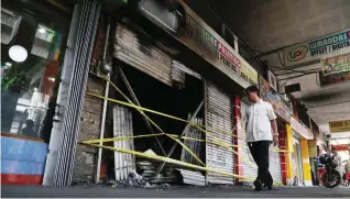  ?? CZAR DANCEL ?? MALAGIM NA CHRISTMAS PARTY Napapating­in ang mga taong dumaraan sa nasunog na printing shop sa Claro M. Recto Avenue, sa Maynila, kahapon. Tatlo ang namatay sa insidente na pawang trabahador sa shop.