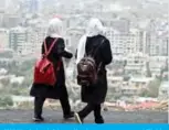  ?? — AFP ?? KABUL: Schoolgirl­s walk along a street at a hillside overlookin­g Kabul.