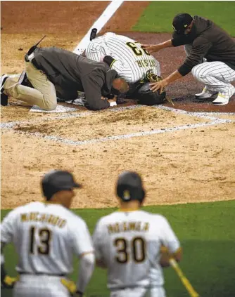  ?? DENIS POROY GETTY IMAGES ?? A trainer and manager Jayce Tingler (right) attend to the injured Fernando Tatis Jr. on Monday night.