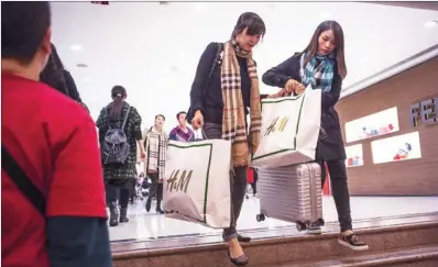  ?? DAVID PAUL MORRIS / BLOOMBERG ?? Shoppers carrying upmarket brand products at Harbour City shopping mall in Tsim Sha Tsui — one of Hong Kong’s prime shopping districts. The SAR, once seen as a shopping paradise for mainland visitors, has seen retail sales slump as visitor numbers...