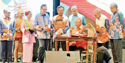  ??  ?? NAJIB (duduk) menandatan­gani Buku Khas sambutan Hari Malaysia 2017 sambil diperhatik­an oleh tetamu kehormat yang lain. -Foto oleh James Tseu
