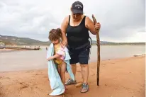  ?? OLIVIA HARLOW/THE NEW MEXICAN ?? Loretta Pacheco King of Santa Fe puts a towel around her 3-yearold granddaugh­ter, Sophia Martinez, at Abiquiú Lake after an afternoon thundersto­rm Friday. She said she and her family spent the day at the lake, playing in the water and having a picnic.