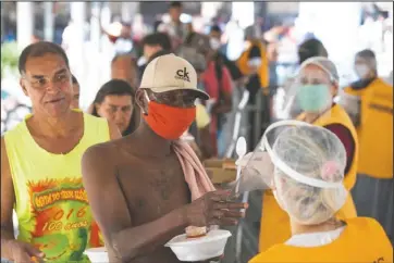  ?? The Associated Press ?? HOMELESS HELP: Volunteers from a Christian church serve food to homeless people during a quarantine imposed by the state government to help contain the spread of the new coronaviru­s in Sao Paulo, Brazil, Monday.