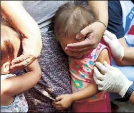  ??  ?? Department of Health and Philippine National Red Cross volunteers conduct house-to-house measles vaccinatio­n for children yesterday at an informal settlers’ community in Manila, which is suspected by the government as the ground zero of the measles outbreak in Metro Manila.