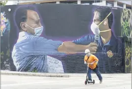  ?? WILFREDO LEE — THE ASSOCIATED PRESS ?? A constructi­on worker rides a scooter past a mural by Hiero Veiga of billionair­e businessma­n Moishe Mana, left, and city of Miami Mayor Francis X. Suarez on Monday in the Wynwood Arts District of Miami.