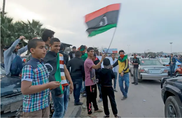  ?? AFP ?? WHITHER PEACE? Libyans wave the national flag in Benghazi . The country lacks a shared national identity — a reality that the current civil war has aggravated. —