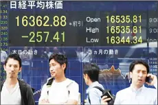  ??  ?? People walk past an electronic quotation board flashing the Nikkei key index of the Tokyo Stock Exchange (TSE) in front of a securities company in Tokyo on July 26. Tokyo shares dropped as a rally in the yen and another fall in oil prices dented...