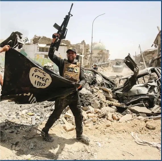  ??  ?? Members of the Iraqi CounterTer­rorism Service (CTS) carry an upside-down IS flag in Mosul