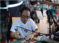  ??  ?? Leo Emmanuel Castro inscribing indigenous Baybayin script onto a piece of bamboo at his shop in Manila. — AFP photos