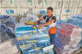  ?? AP PHOTO/HASSAN ESLAIAH ?? A United Nations worker prepares aid for distributi­on to Palestinia­ns on Oct. 23 at UNRWA warehouse in Deir Al-Balah, Gaza Strip.