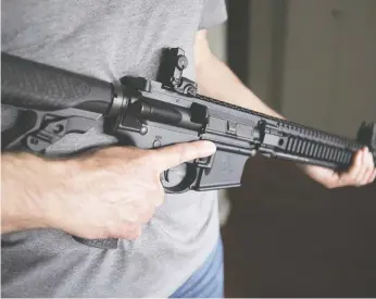  ?? JONATHAN HAYWARD / THE CANADIAN PRESS FILES ?? A restricted licence-holder holds a AR-15 at his home in Langley, B.C. Owners of such guns will face new
restrictio­ns on transport and usage, but the Liberals will let you keep it, Matt Gurney writes.