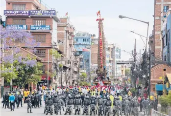  ?? NIRANJAN SHRESTHA/AP ?? Police forces stand guard as devotees pull a chariot of the deity Rato Machindran­ath — whose statue is made from clay and covered in red paint with wide-open eyes — during a Hindu chariot festival Saturday in Lalitpur, Nepal. A truncated version of the festival took place amid COVID-19 restrictio­ns following an deal between organizers and authoritie­s.