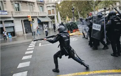  ?? EMILIO MORENATTI/THE ASSOCIATED PRESS ?? A Spanish riot police officer shoots rubber bullets at people trying to reach a polling station in Barcelona, Sunday. Nothing can justify the brute force shown by this democratic country against its people, writes Celine Cooper.