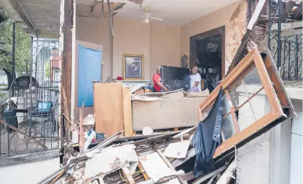  ?? DAVID GRUNFELD/THE ADVOCATE ?? Christophe­r Atkins, left, helps friend George Soloman remove items from his damaged home Monday in New Orleans.