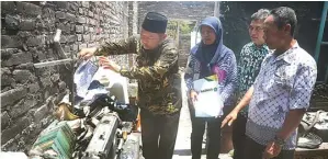  ?? BOY SLAMET/JAWA POS ?? BERIKAN BANTUAN: Abah Ipul melihat lembaran Alquran di rumah Siswandi yang terbakar Ahad lalu.