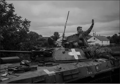  ?? NICOLE TUNG / THE NEW YORK TIMES ?? A Ukrainian soldier waves to passing buses near the recaptured village of Verbivka, Ukraine, on Tuesday. The U.S. has its share of the credit as Ukrainian troops have been regaining ground Russia had taken in its invasion this year.