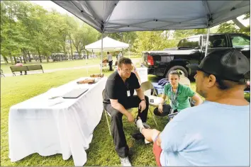  ?? Peter Hvizdak / Hearst Connecticu­t Media ?? Nurse practition­er Philip Costello, clinical director of homeless care at the Cornell Scott Hill Health Center, left, with Dr. Emily Pinto Taylor of Yale New Haven Hospital, inspect the foot of a passerby on the New Haven Green Friday morning, the site of an an epidemic drug overdose from K2, a synthetic marijuana.