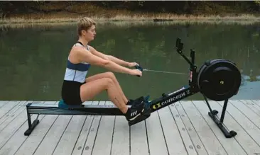  ?? MELISSA LUKENBAUGH/THE NEW YORK TIMES ?? A rowing team member demonstrat­es the drive position on a rowing machine.