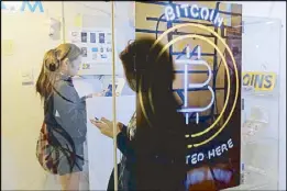  ??  ?? People use a Bitcoin automated teller machine in Hong Kong on Friday. Bitcoin is the world’s most popular virtual currency.