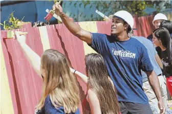  ?? STAFF PHOTO BY MATT STONE ?? MAKING HIS MARK: Patriots defensive back Eric Rowe helps volunteers paint a fence during a community event at Bridge Over Troubled Waters yesterday.