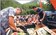  ?? THOMAS PETER / REUTERS ?? Volunteers hand out fruit on Thursday to locals housed in a tent camp after their homes were damaged by the earthquake in Jiuzhaigou, Sichuan province, on Tuesday.