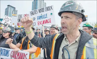  ?? CP PHOTO/PAUL CHIASSON ?? Striking constructi­on workers walk the picket line in front of a constructi­on site Wednesday in Montreal. A union alliance representi­ng about 175,000 Quebec constructi­on workers has launched an unlimited general strike.