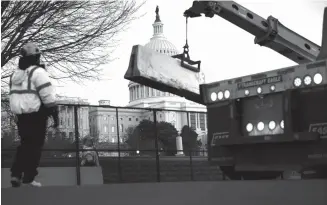  ?? BRENDAN SMIALOWSKI/AFP ?? PASCARUSUH: Para pekerja memperkuat pagar pengendali massa di sekitar Capitol Hill dengan penghalang beton Kamis (7/1), sehari setelah massa pendukung Presiden Amerika Serikat Donald Trump masuk ke gedung itu.