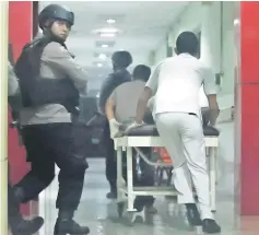  ??  ?? Photo shows armed police securing a corridor of a hospital in Medan, North Sumatra province, after they shot dead one of two terror suspects during gun fighting. — AFP photos