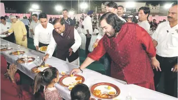  ?? — AFP photo ?? Ambani (centre) at Reliance Industries with his son Anant (fourth right) attending to guests during Anna Seva (community food service) to seek blessings from various community members for the pre-wedding celebratio­n of Anant Ambani and Radhika Merchant in Jamnagar.