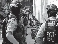  ?? HONG KONG ?? Anti govt demonstrat­ors sit as they were detained during a lunch time protest in Hong Kong, China.