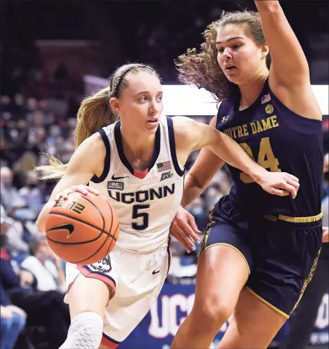  ?? Jessica Hill / Associated Press ?? UConn’s Paige Bueckers dribbles around Notre Dame’s Madelyn Westbeld on Dec. 5. Bueckers had knee surgery Monday; the university said her recovery time is estimated at eight weeks from her surgery date.