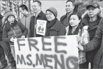  ?? CP PHOTO ?? People hold a sign at a B.C. courthouse prior to the bail hearing for Meng Wanzhou, Huawei’s chief financial officer on Monday.