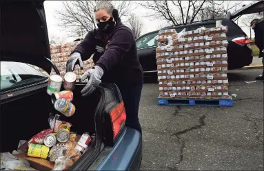  ?? Erik Trautmann / Hearst Connecticu­t Media ?? Norwalk Deputy Director of Emergency Management Michele DeLuca helps put food in a family’s car as the Connecticu­t Food Bank holds a distributi­on event at Calf Pasture Beach in Norwalk on Wednesday.