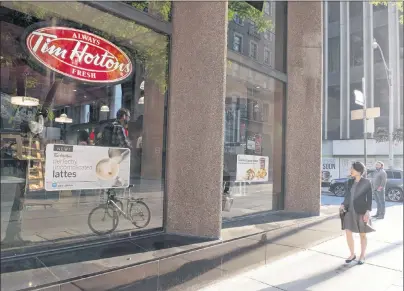  ?? CP PHOTO ?? A woman walks past a Tim Hortons in Toronto on Aug. 2, 2017. The parent company of Tim Hortons says restaurant­s in select markets have increased prices on certain breakfast items.