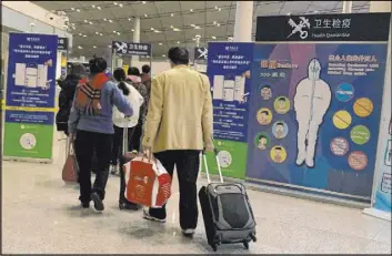  ?? Ng Han Guan The Associated Press ?? Travelers pass a health checkpoint before entering immigratio­n at the internatio­nal airport in Beijing. Centers for Disease Control and Prevention staffers will screen passengers arriving from central China at three U.S. airports for a new virus.