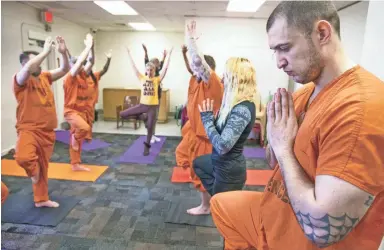  ?? PHOTOS BY TOM TINGLE/THE REPUBLIC ?? Inmate Erik VanVoorhis, right, and volunteer Allison Merlo, second from right, practice yoga during a class offered by the Prison Yoga Project Phoenix at the Maricopa County Towers Jail complex Friday.