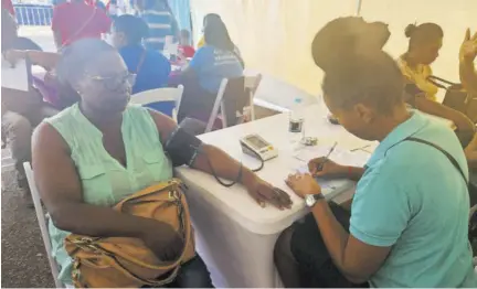  ?? ?? Community health aid Anessa Thompson (right) checking Deon Boothe’s blood pressure during last Friday’s health fair in Mandeville.